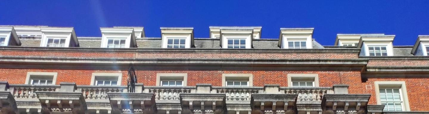 A large traditional apartment block in Grosvenor Square, London set against a blue sky