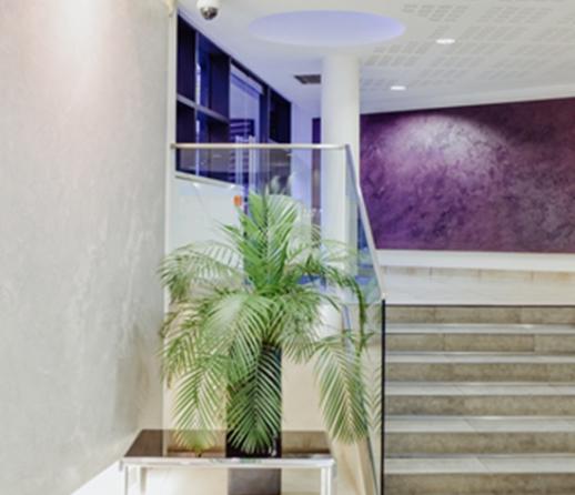 Modern lobby area of an apartment building showing white walls, purple feature wall and a glass bannister