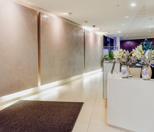 Modern lobby area of an apartment block. with white tiled floor, downlighters and neutral wall colours