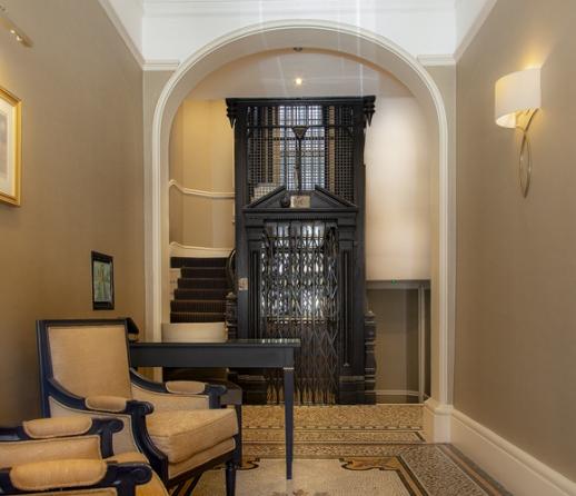 The lobby area of an old apartment block with old fashioned lift
