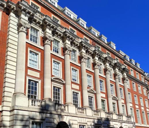 A large traditional apartment block in Grosvenor Square, London set against a blue sky