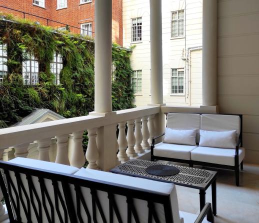 An apartment balcony with two outdoor sofas with cream cushions