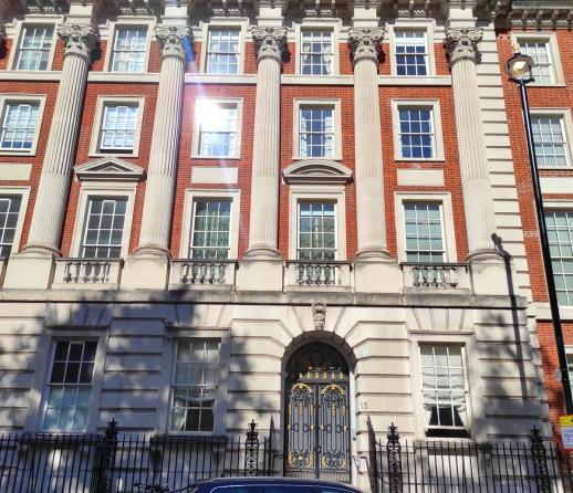 A large traditional apartment block in Grosvenor Square, London set against a blue sky
