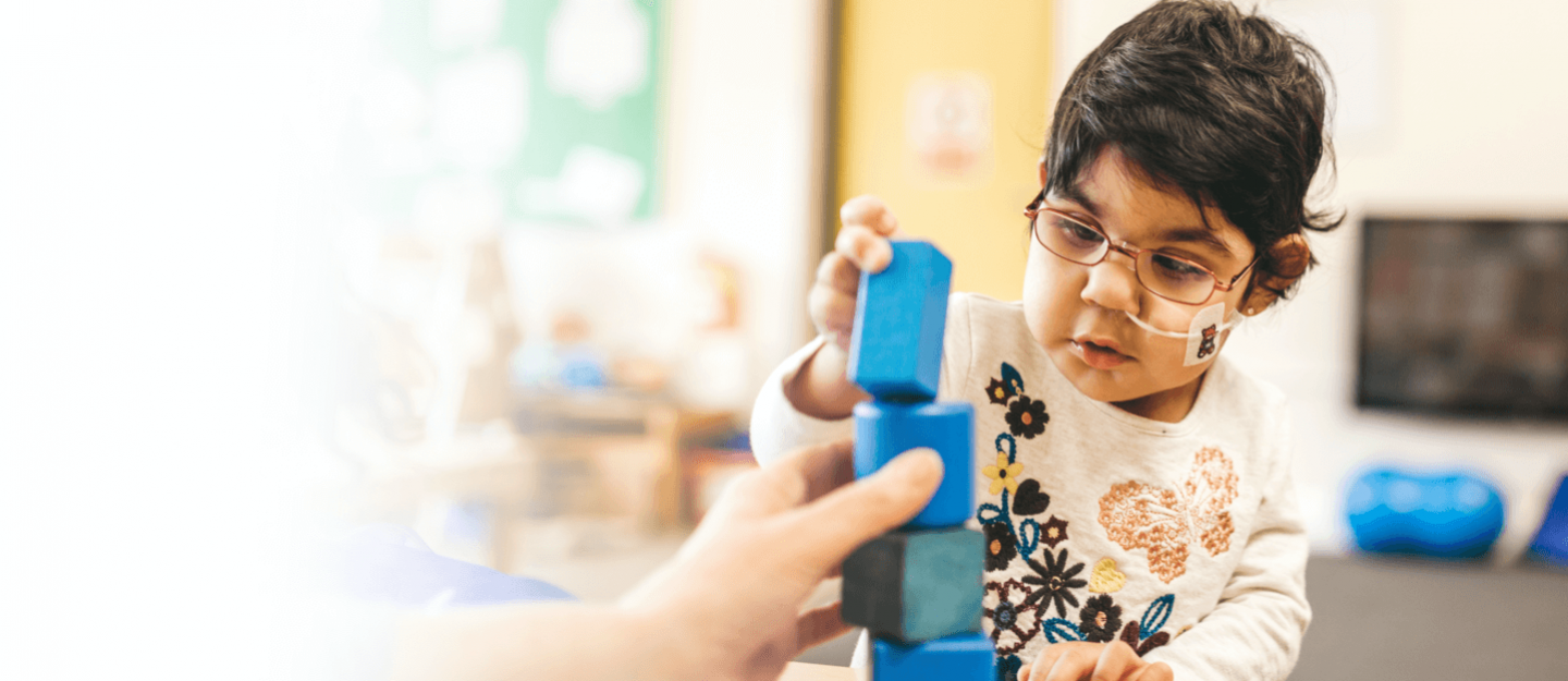 A child playing with blue and green building blocks.